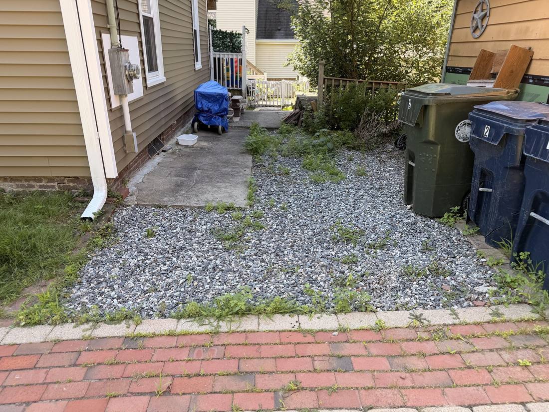 The original driveway — loose gravel, weeds through the ruts and no edge restraint