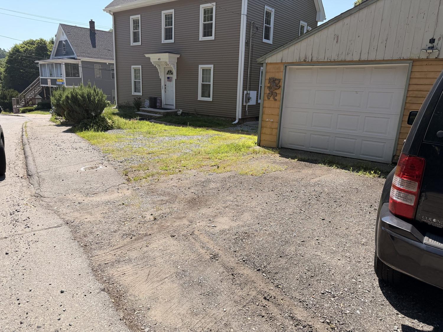 Before — a rutted gravel track with grass down the middle, looking up toward the garage
