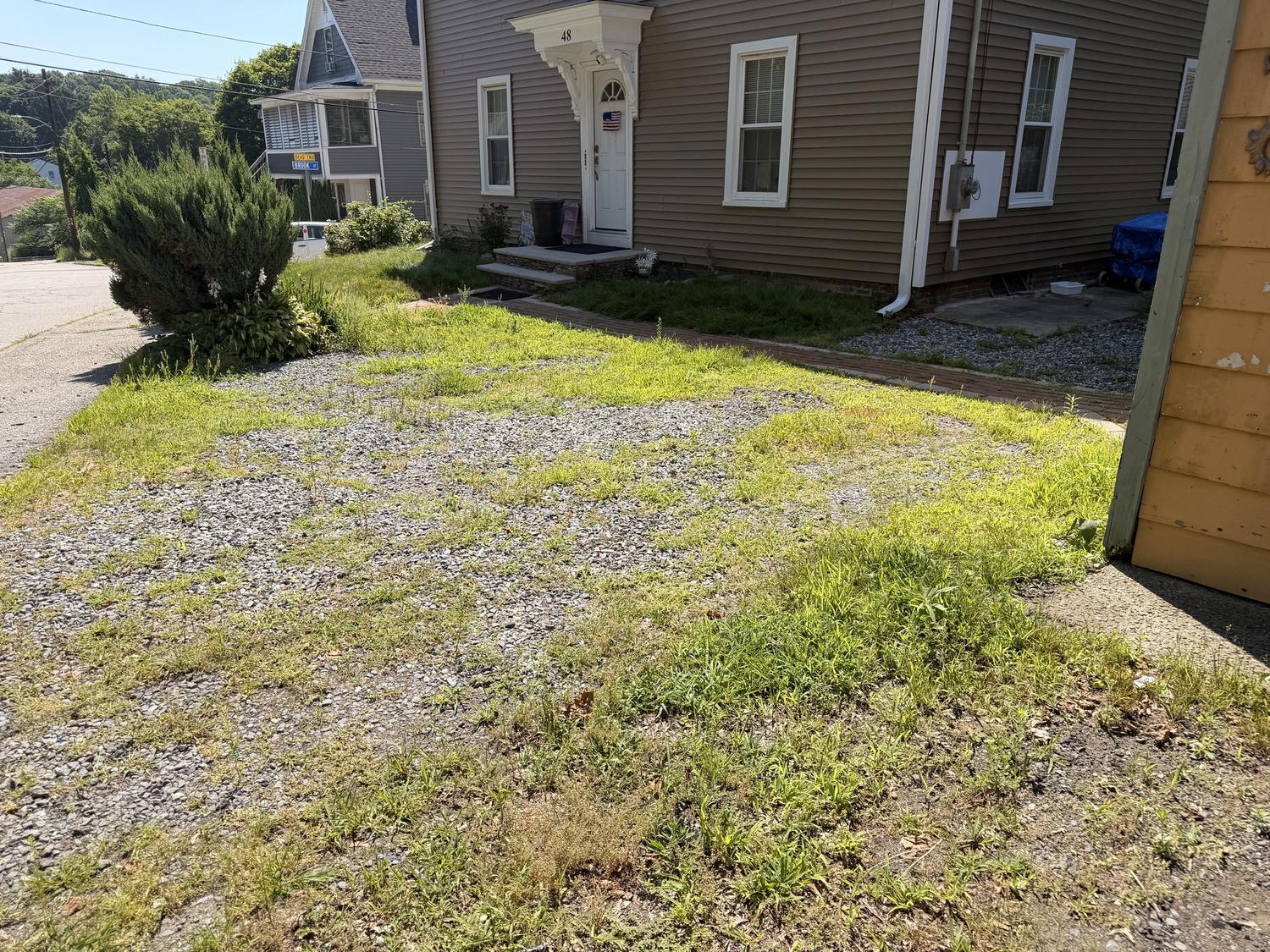 Before — weeds and loose stone in the side entry between the houses