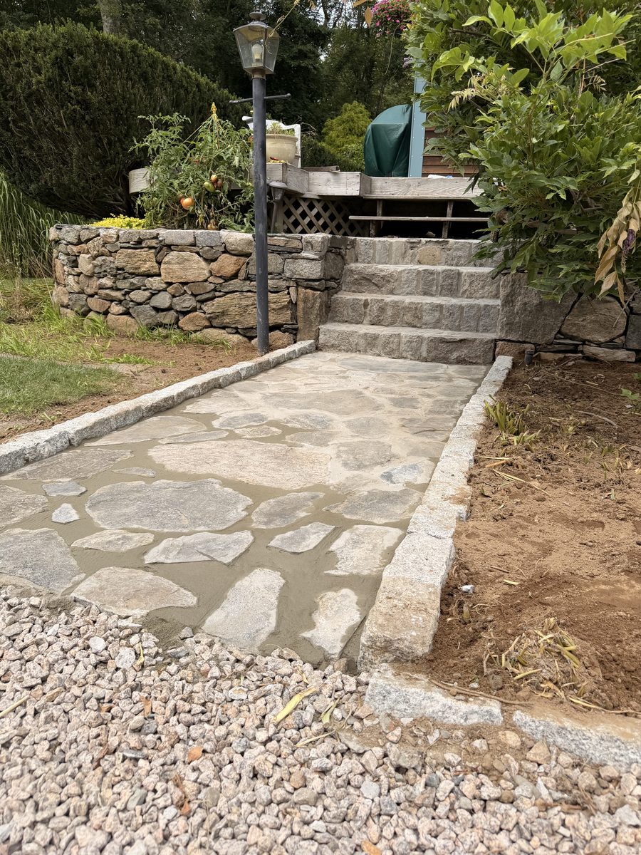 Finished flagstone walk edged in granite cobble, running to granite steps