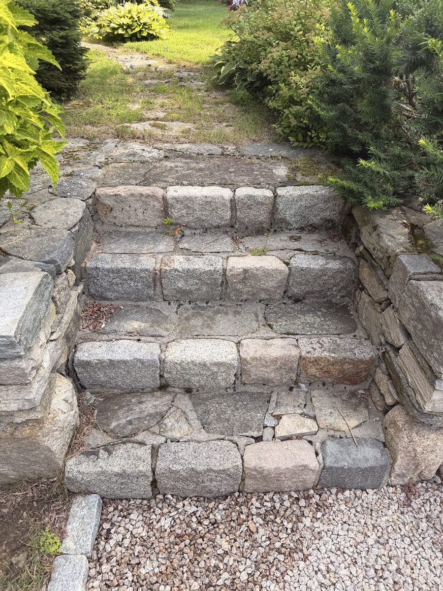 Before — narrow cobble steps sunk out of level, weeds through the joints, landing straight onto the gravel drive