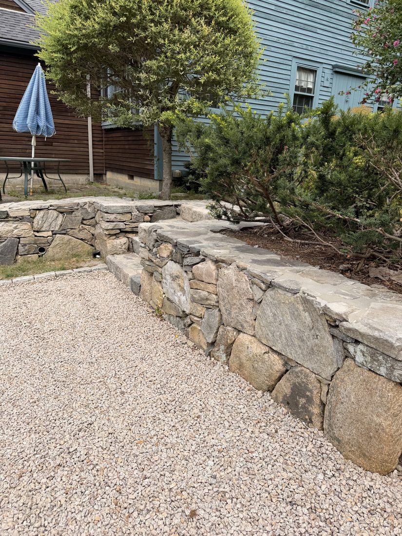 A dry-laid fieldstone wall running the length of the driveway, capped flat