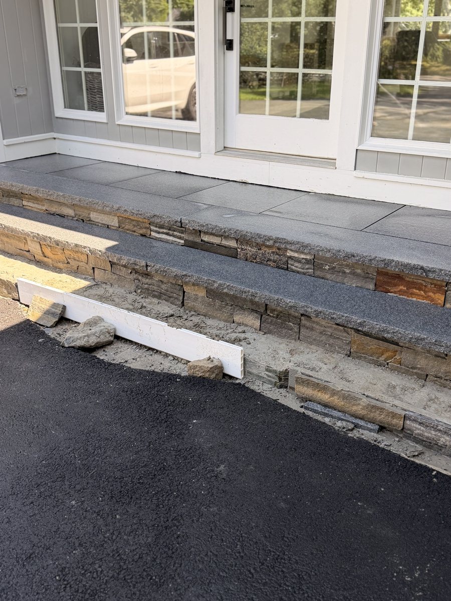 The finished flight from the drive in full sun, the riser stone reading warm under the grey treads