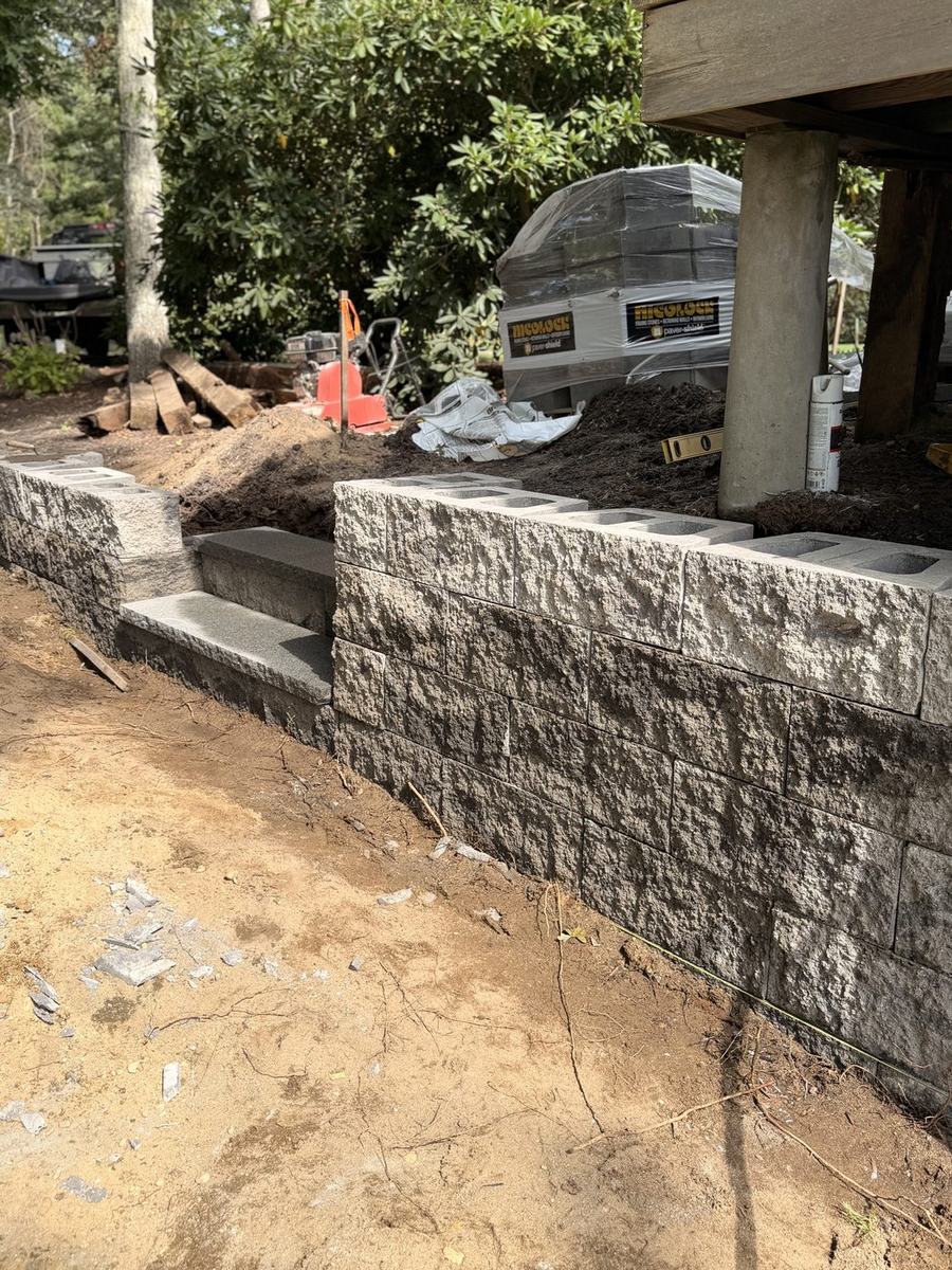 Block retaining wall with granite steps, seen down the run