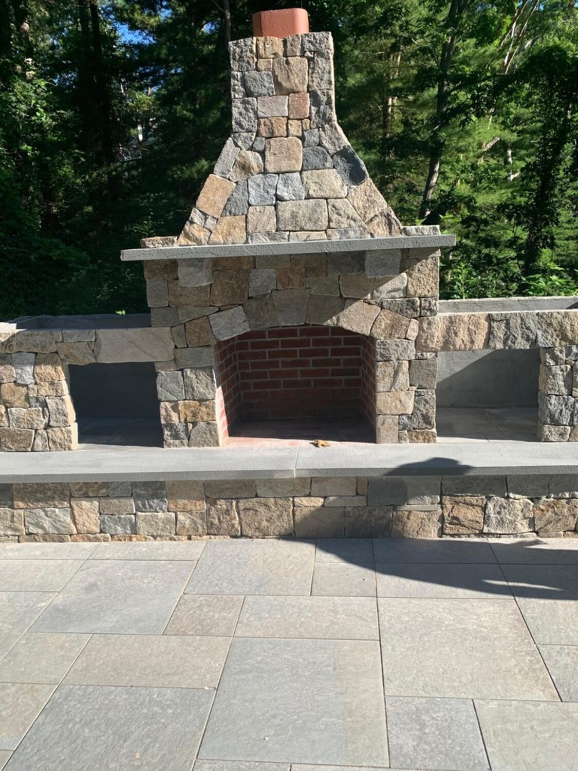 Outdoor stone fireplace and bluestone patio built by PHAÖRA in Massachusetts